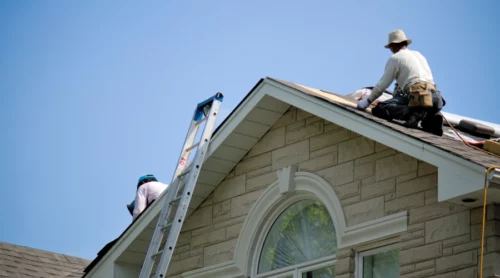 renovation appraisal of a beige house with light brown roofing and some workers on top